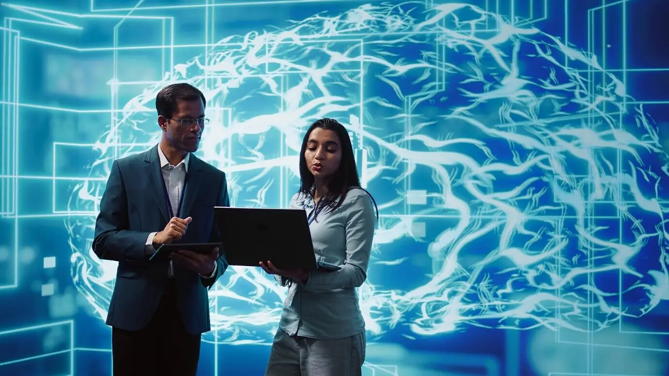Compañeros de trabajo que resuelven tareas en un portátil y una tableta con software de IA en ejecución.
