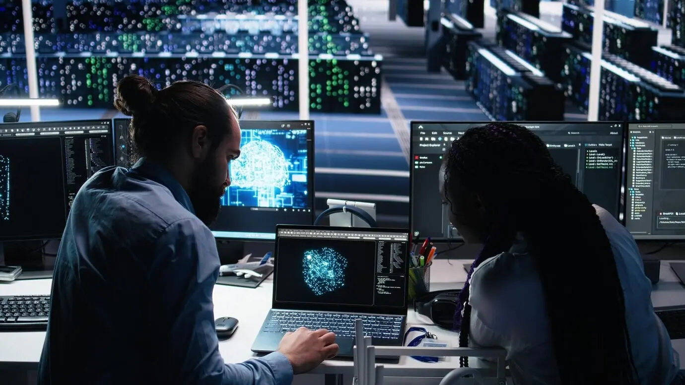 Administrador de centro de datos enseña a un becario a monitorizar una red neuronal mediante IA.