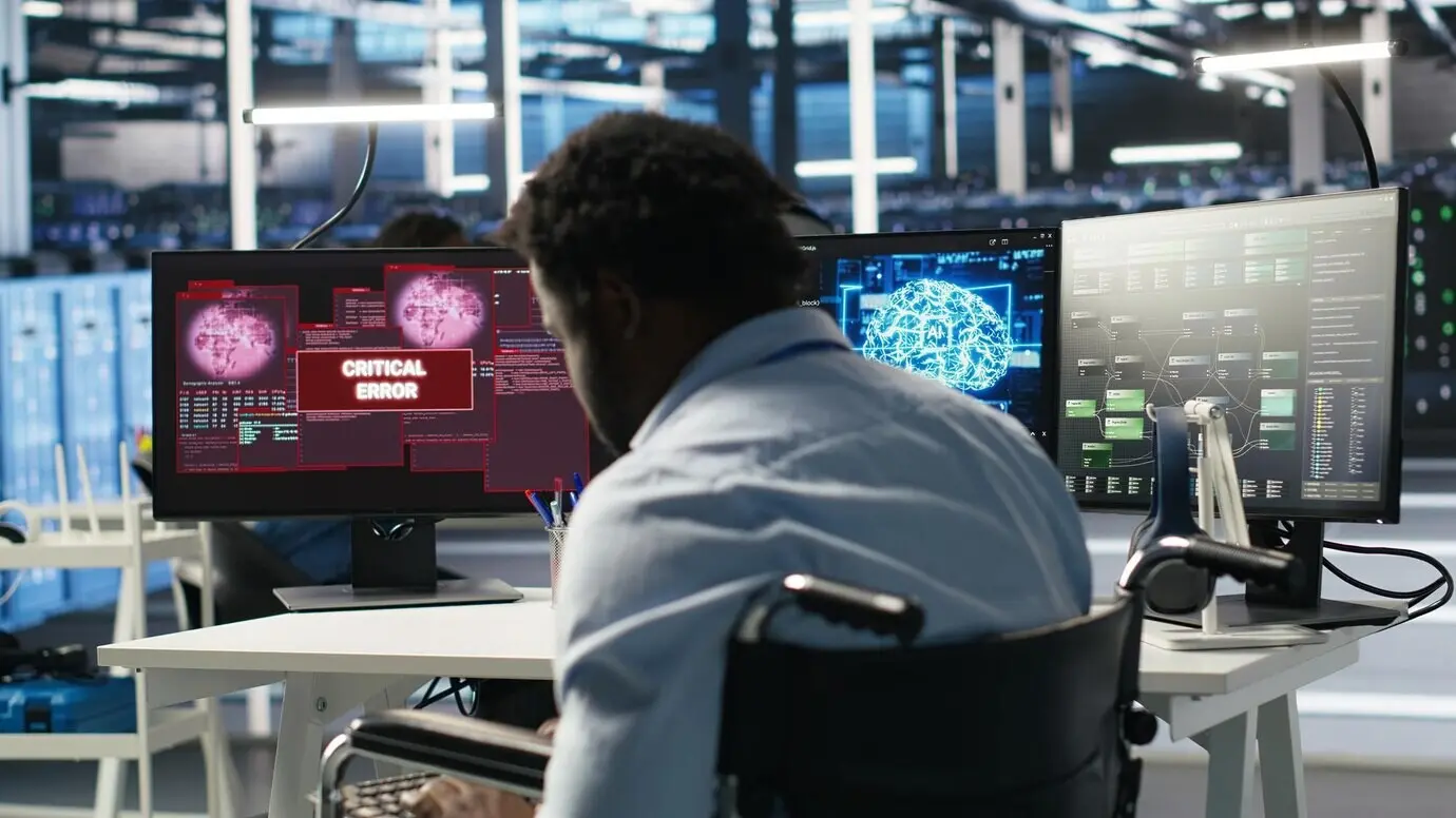 Hombre sobrecargado de trabajo en silla de ruedas, molesto por una ventana emergente de advertencia de error mientras mira las analíticas de IA del centro de servidores.